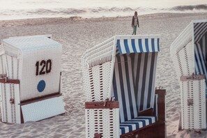 Una playa con sillas y una persona de pie sobre una de ellas.
