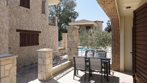Un bâtiment en pierre doté d’un patio comprenant une table et des chaises, une piscine et une vue sur le paysage environnant.