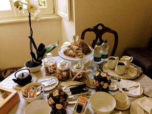 A table set for a tea service with pastries, a teapot, cups, and a vase of flowers. - La Belle Coquette B&B (Como)