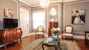 A traditional living room with a television, two armchairs, a coffee table, and a chandelier.