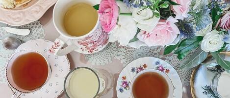A table set with pancakes, tea, and a floral arrangement.