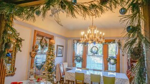 A dining area with a chandelier, Christmas decorations, and a table set for four.