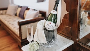 A bottle of champagne in a glass bucket on a marble table, with two glasses and a white cloth nearby.