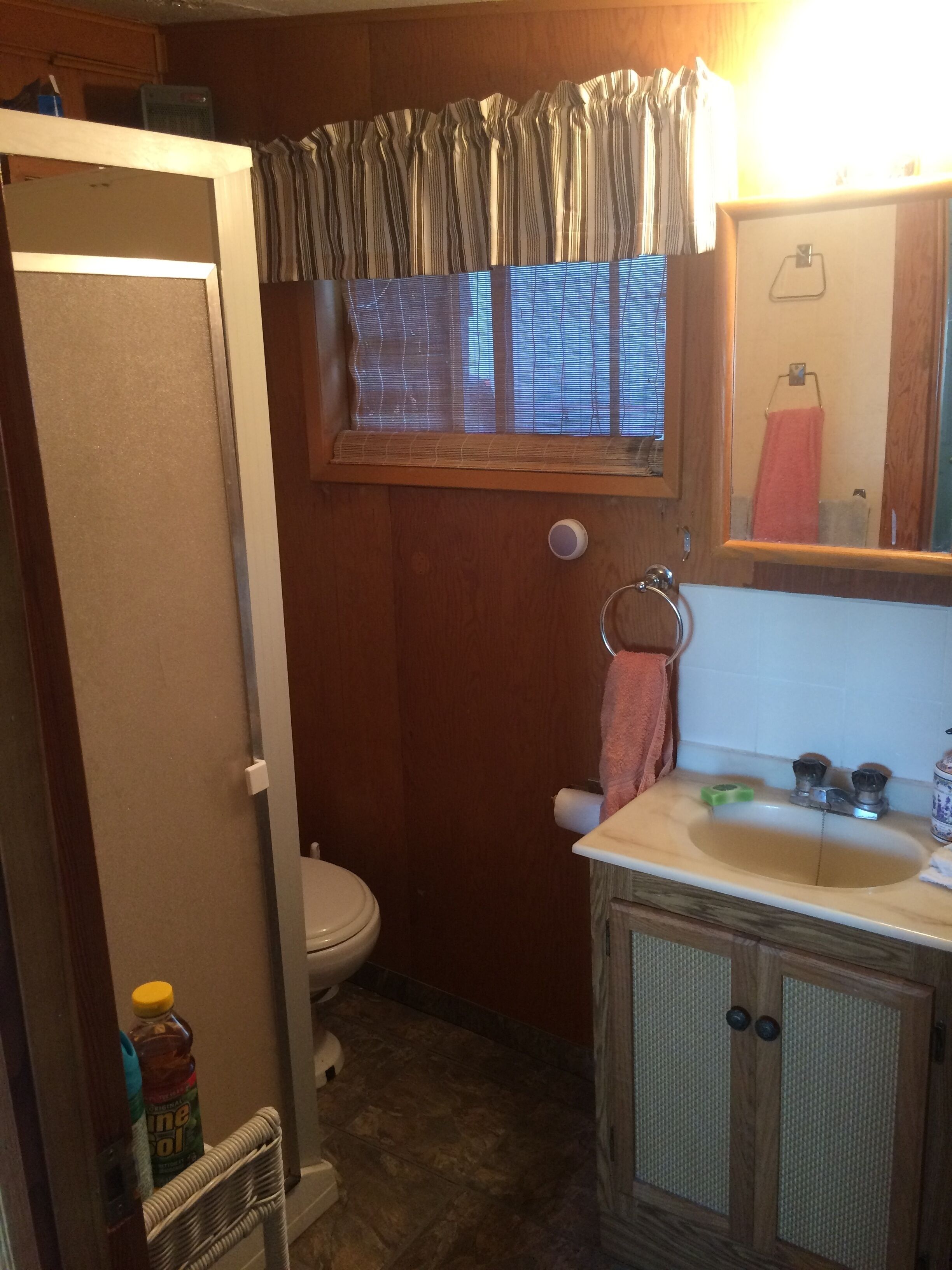 Une petite salle de bain comprenant des toilettes, un lavabo et une fenêtre avec des stores.