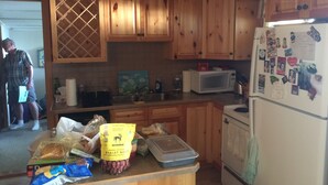 Une cuisine avec des meubles en bois, un four à micro-ondes, un réfrigérateur et un plan de travail sur lequel se trouvent divers objets, notamment un sachet de dattes biologiques.