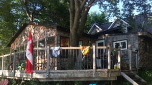 Une terrasse en bois avec un drapeau, une chaise et une maison en arrière-plan.