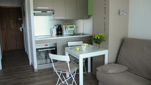 Une cuisine compacte avec une table blanche, un canapé beige et un petit coin repas.