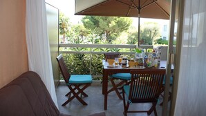 Un balcon avec une table, des chaises et un parasol.
