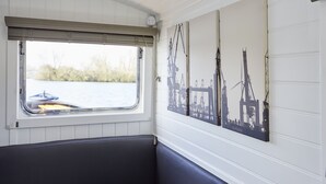 Une cabane dotée d’une fenêtre, d’un banc et de trois œuvres d’art fixées au mur, représentant des scènes industrielles.