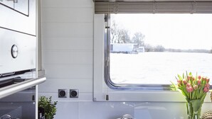 Une cuisine moderne équipée d’une cuisinière, de casseroles, d’un évier et d’une fenêtre donnant sur un paysage enneigé.