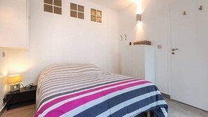 Ett sovrum med en säng, ett nattduksbord, en lampa, en vägglampa och en dörr.
