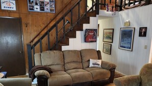 Un salon chaleureux avec un canapé marron, une table basse en bois et un escalier.
