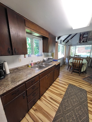 A kitchen with wooden cabinets, a granite countertop, a sink, and a dining area with a table and chairs.