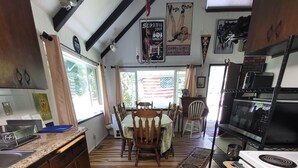 Une cuisine avec un plancher en bois, un coin repas avec des chaises, une cuisinière et un réfrigérateur.