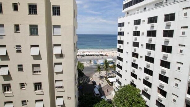 A high-rise building with multiple balconies overlooking a beach. - Apartments Almirante Gonçalves (Rio de Janeiro)