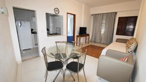 A compact living space with a dining area, kitchenette, and a sofa. - Apartments Almirante Gonçalves (Rio de Janeiro)