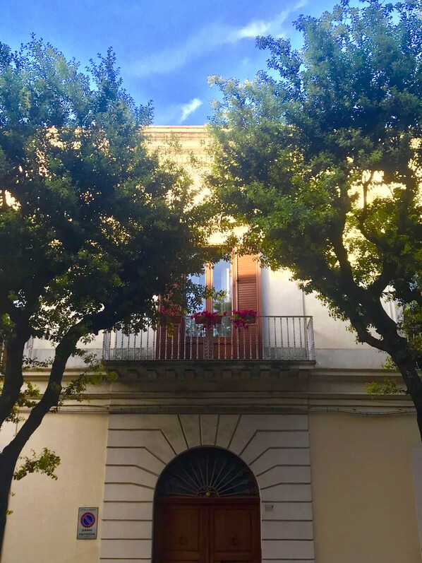 A building with a balcony, a wooden door, and a no parking sign.