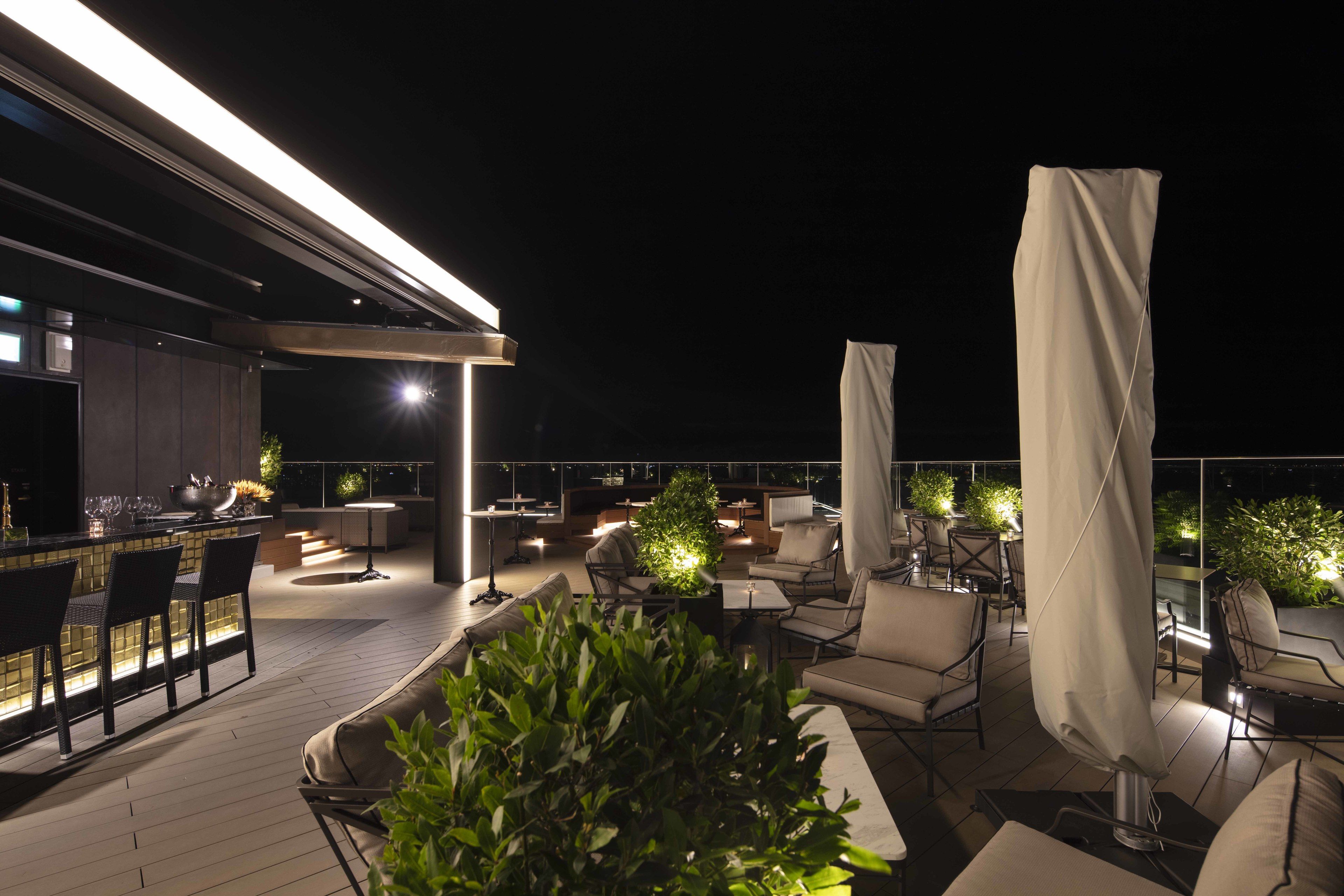 An outdoor terrace with seating, a bar, and ambient lighting.