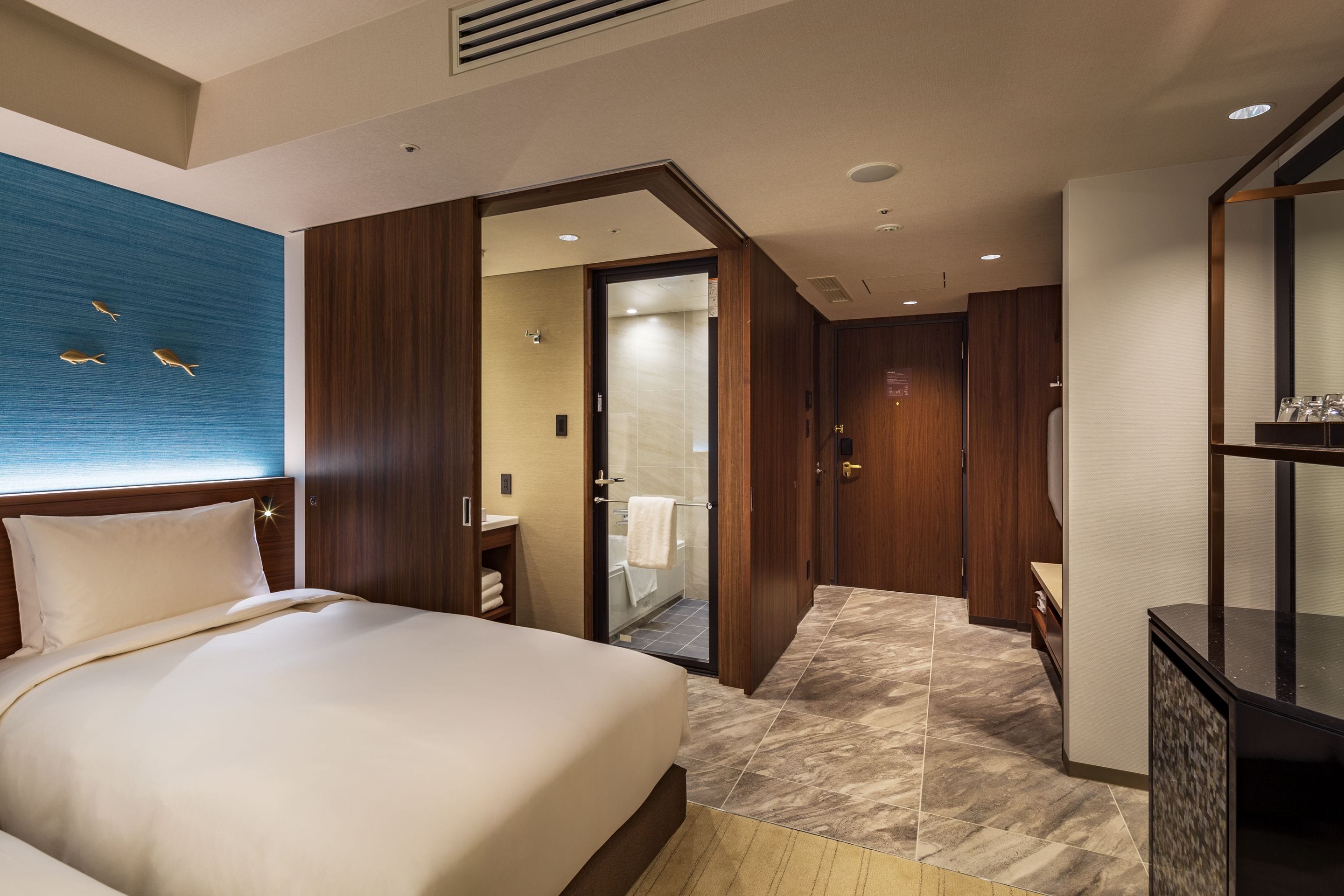 A hotel room with a bed, a bathroom with a shower, and a TV.