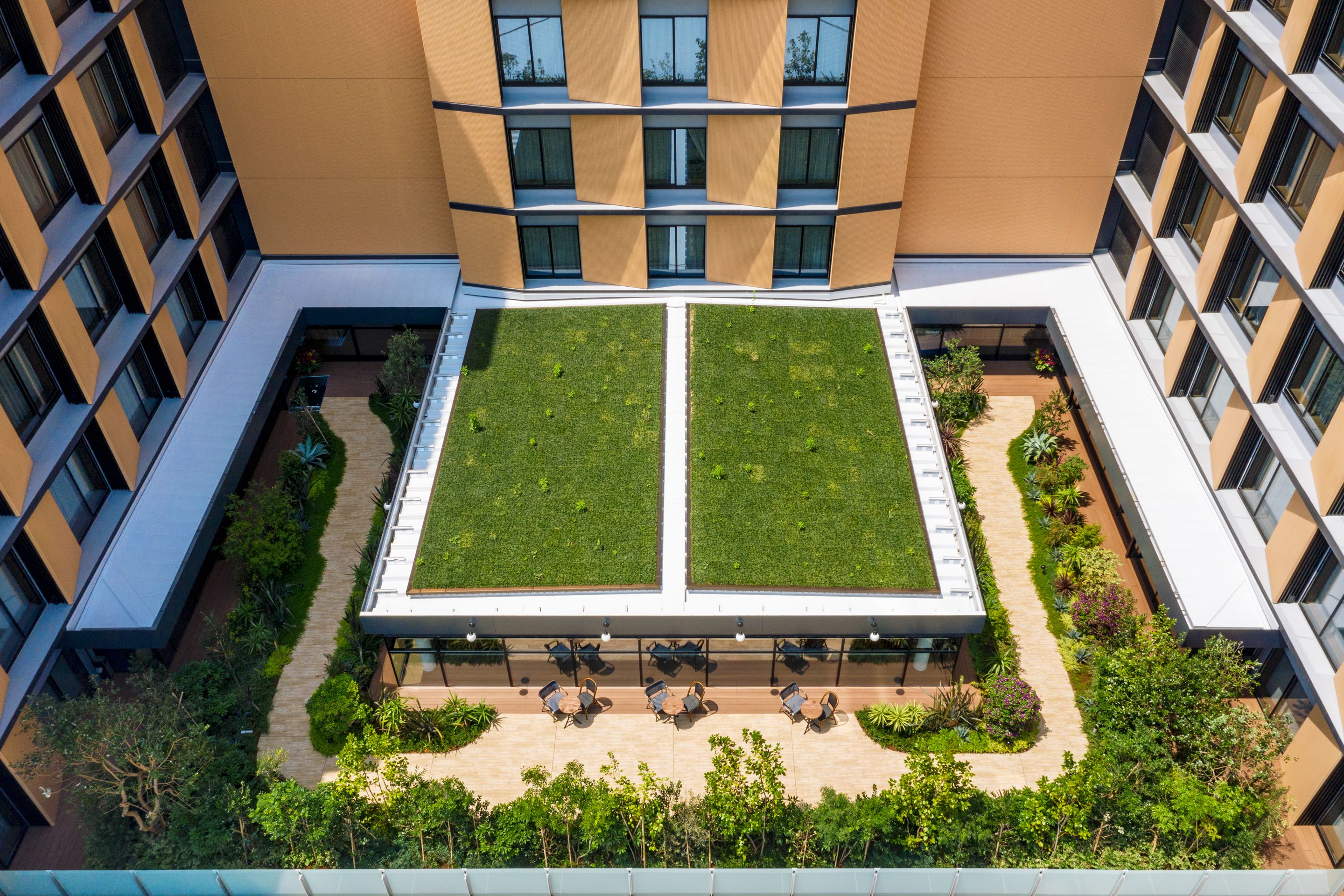 Un bâtiment moderne doté d’une cour intérieure comprenant deux espaces verts et des aires de repos.