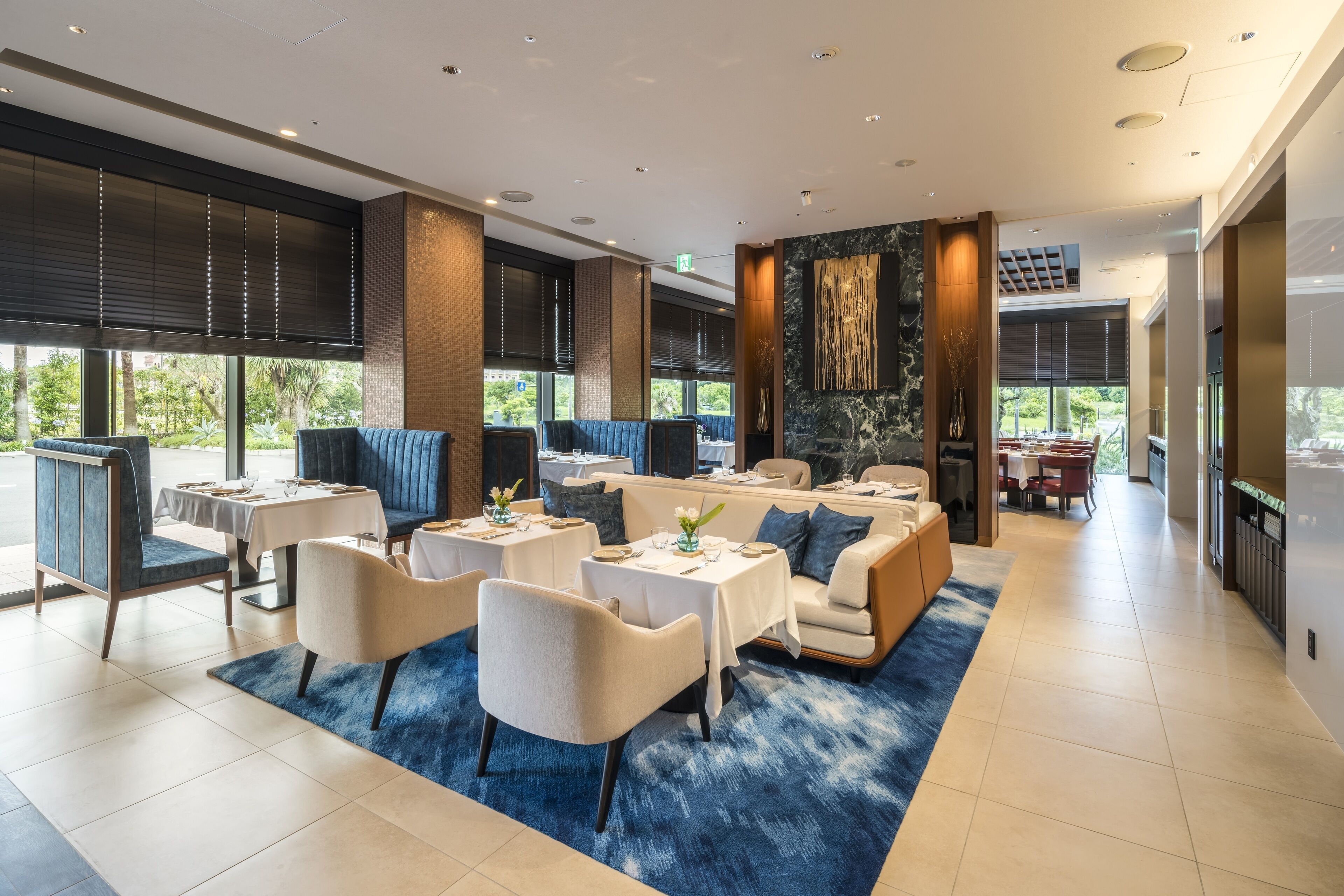 A modern dining area with tables and chairs, a sofa, and a fireplace.