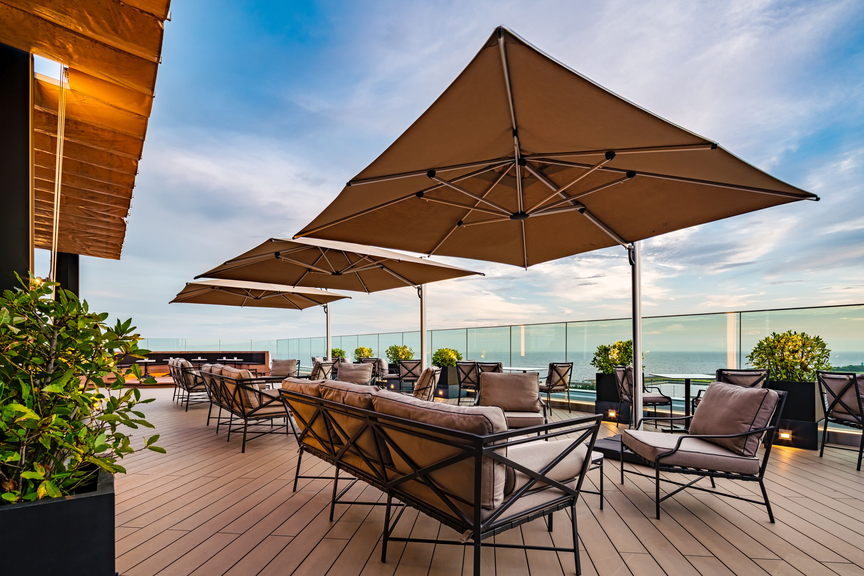 A rooftop terrace with outdoor seating, umbrellas, and potted plants.