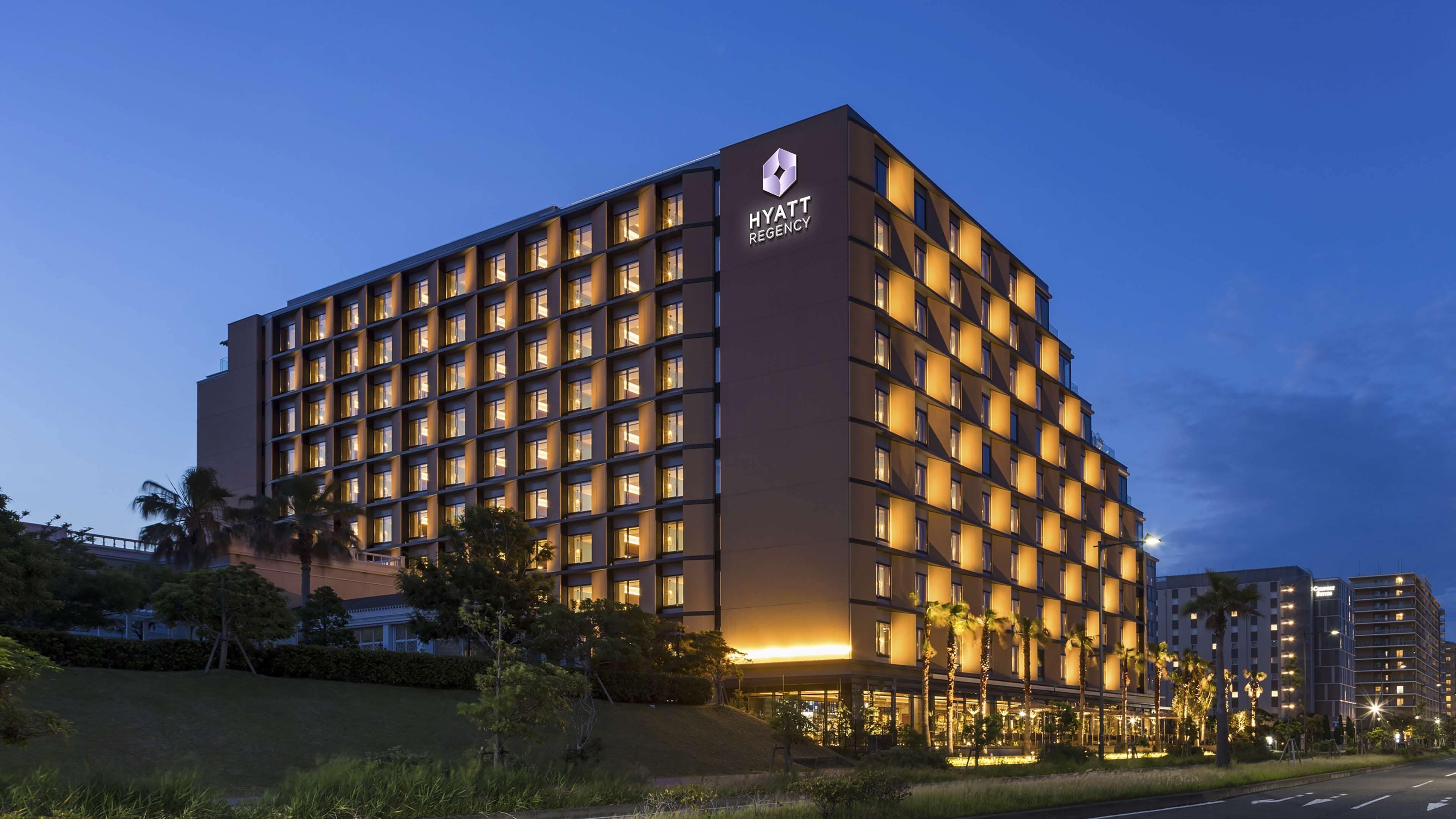 Um hotel de vários andares com design moderno, exibindo uma marca bem visível no topo.