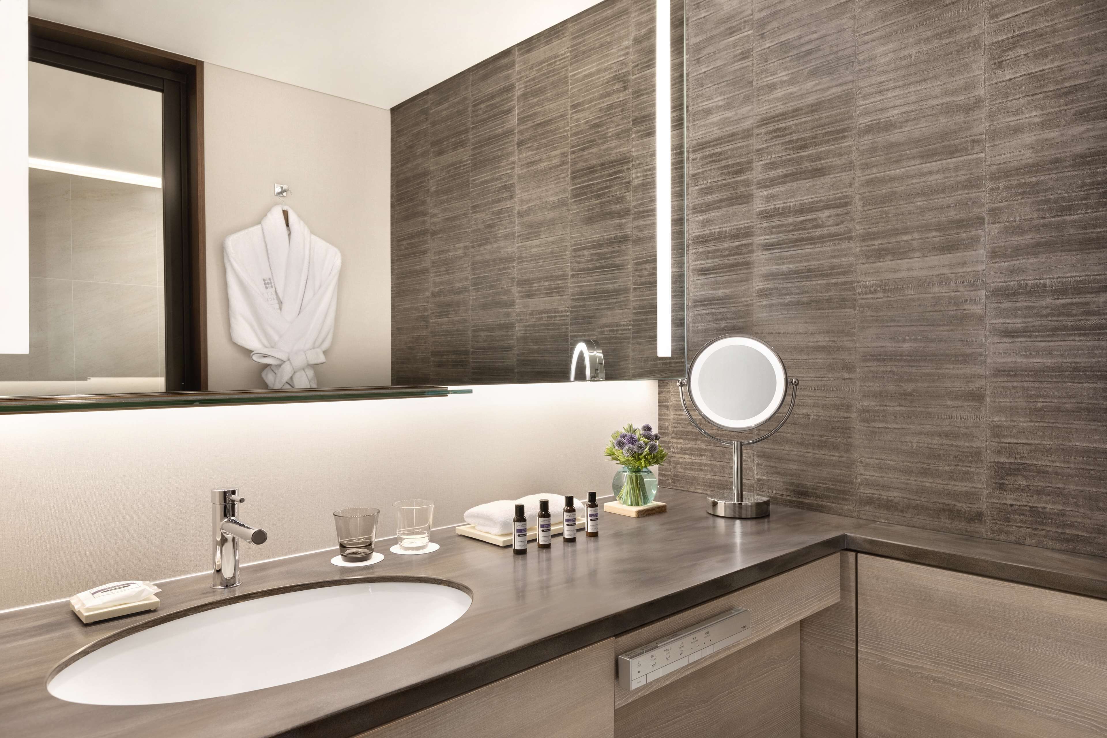 A modern bathroom with a large sink, a mirror, and a towel rack.