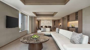 A modern living room with a large sofa, a round coffee table, and a flat-screen TV.
