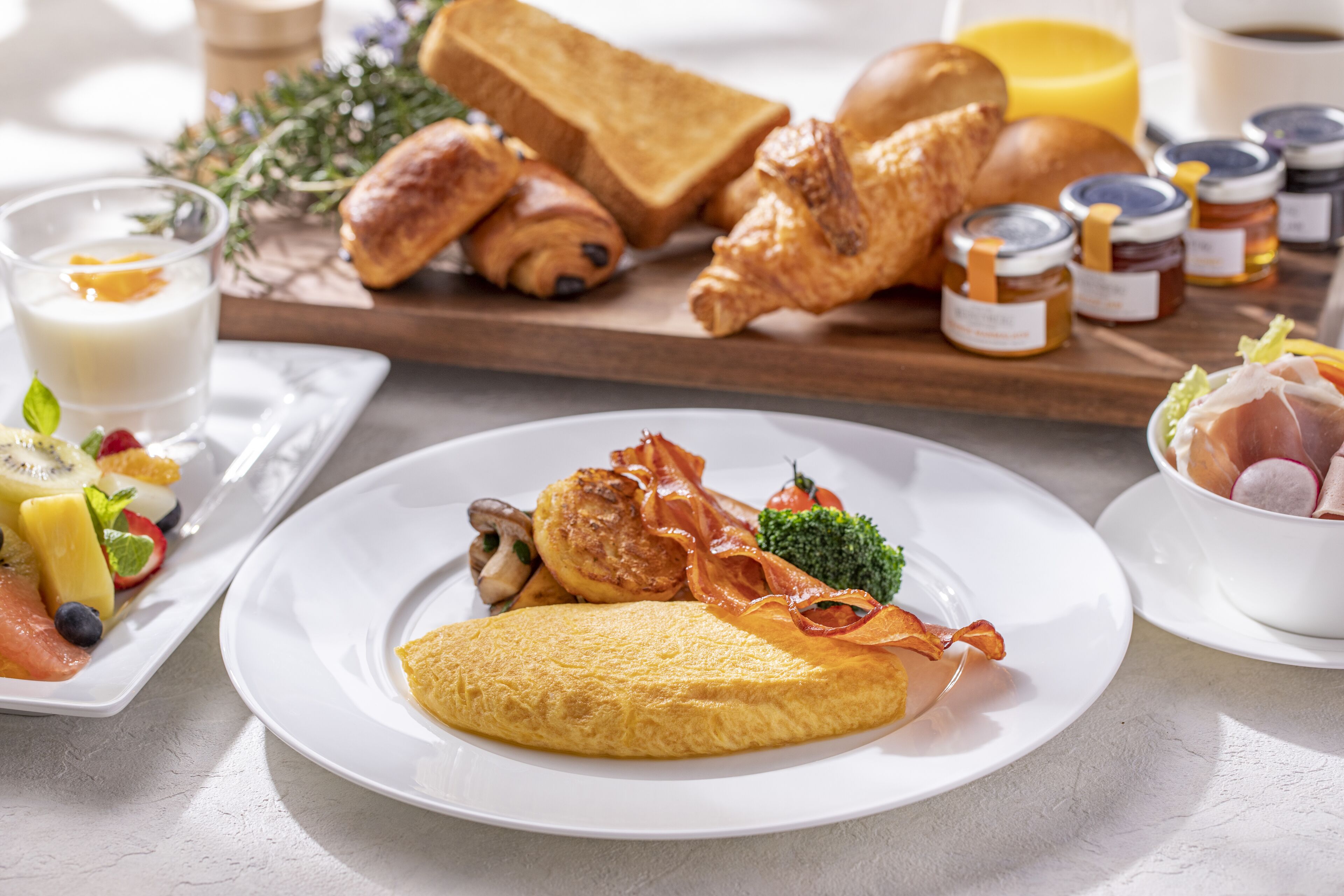 A breakfast setting with an omelette, bacon, vegetables, and toast on a plate.