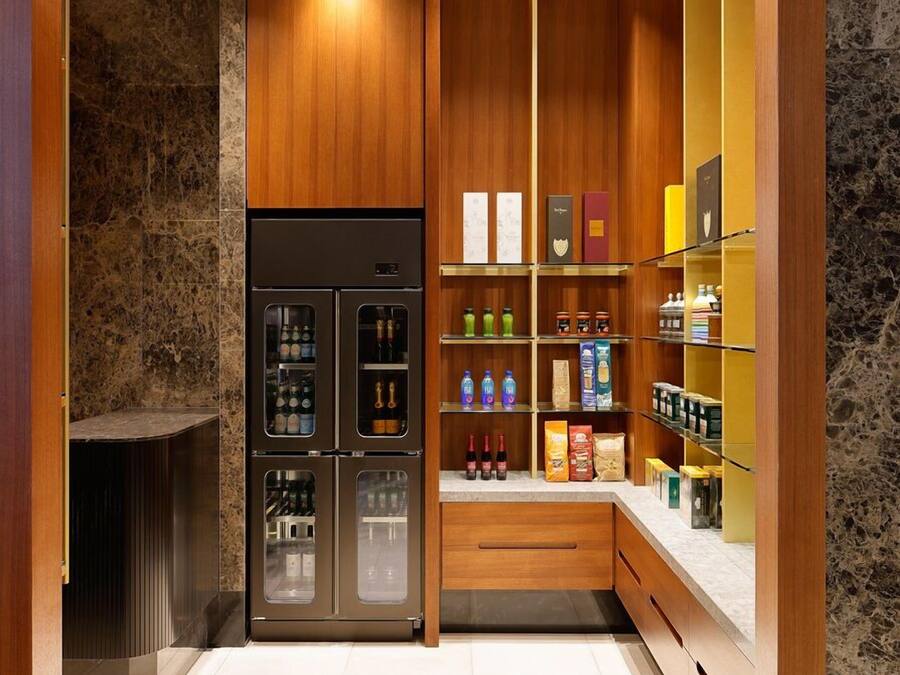 Uma cozinha moderna com frigorífico embutido, armários de madeira e painel de parede de mármore.