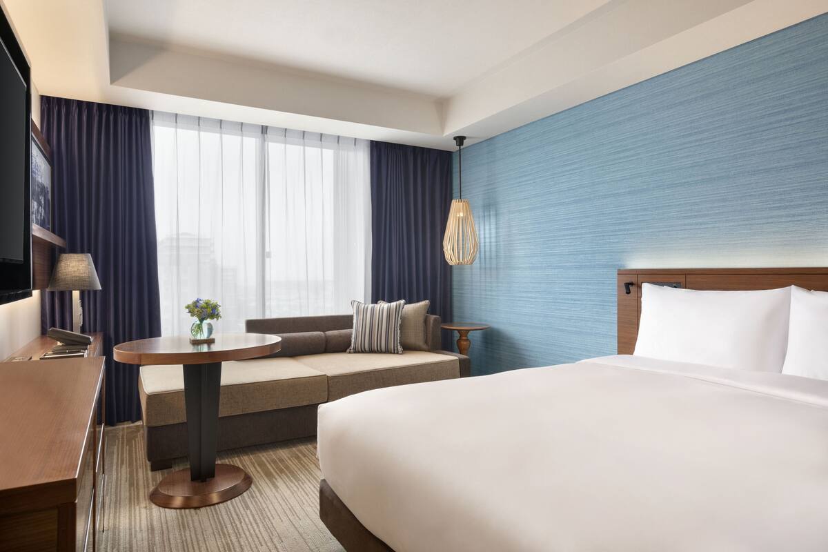 Ein Hotelzimmer mit einem großen Bett, einer Couch, einem kleinen Tisch und einem Fernseher.