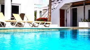 A pool area with white lounge chairs and a palm tree. - One Bedroom vacation apartment Aruba, pool,  walking distance to Eagle Beach! (Bubali 123G)