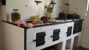 A kitchen with white tiled walls, a black countertop, and cabinets with black handles. There are jars, vegetables, and kitchen utensils on the counter. - Beautiful country house with terrace and garden, ideally located (Cittanova)