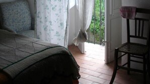 A room with a bed, a chair, a curtain, and a door leading outside. - Beautiful country house with terrace and garden, ideally located (Cittanova)
