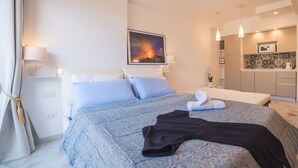 Een moderne hotelkamer met een groot bed, een schilderij aan de muur, een kitchenette en een badkamer met douchegordijn.