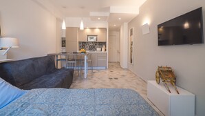 Een moderne hotelkamer met een bed, een bank, een zithoek en een aan de muur bevestigde televisie.