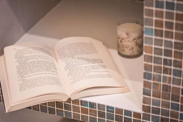 Un libro abierto sobre una superficie blanca, con una vela de cristal a su lado.
