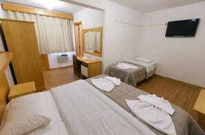 A hotel room with a large bed, a smaller bed, a desk with a chair, a mirror, and a television on the wall. - Hotel 13 Linden (Treze Tilias)