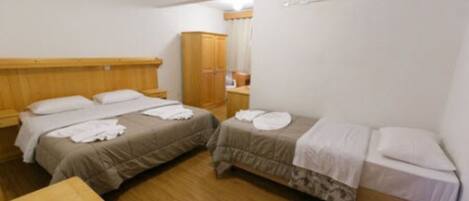 A room with two beds, a wooden wardrobe, and a small table.