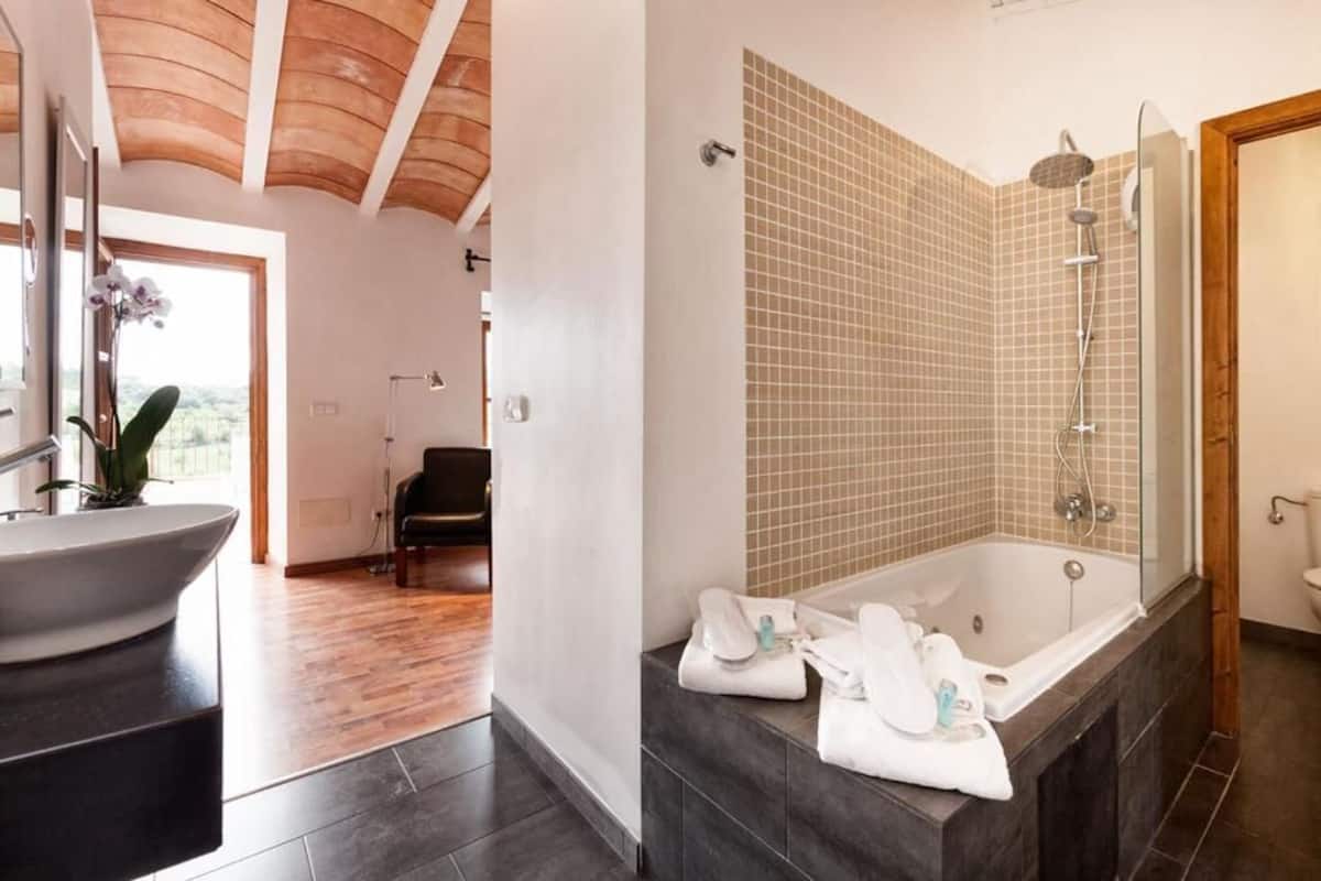 Un baño moderno con una bañera grande, zona de ducha separada y tocador con lavamanos y espejo.