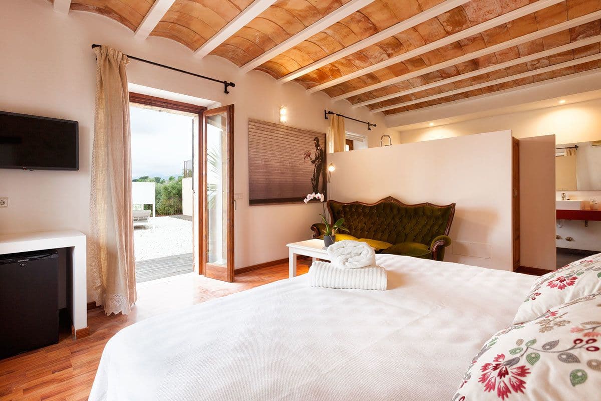 Un dormitorio con cama, escritorio, silla, televisión y puerta corrediza a un balcón.