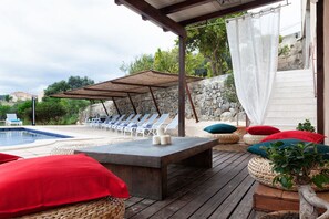 A poolside area with lounge chairs, a wooden deck, and a stone wall. - Hotel Can Riera (Selva)