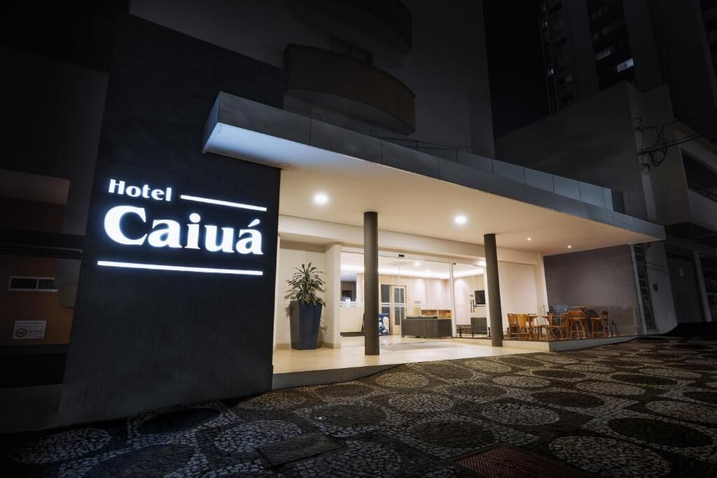 Entrada de hotel con diseño moderno, un gran letrero iluminado y una zona de recepción con asientos.