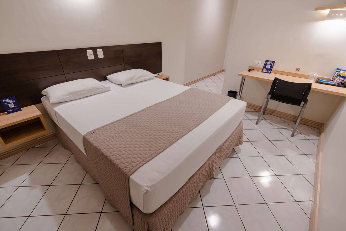 Una habitación de hotel con una cama grande, un escritorio y una silla.