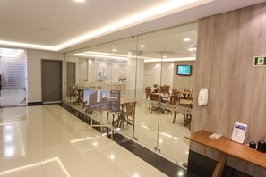 A modern hotel lobby with glass walls, wooden furniture, and a reception desk. - Hotel Caiuá Express Umuarama (Umuarama)