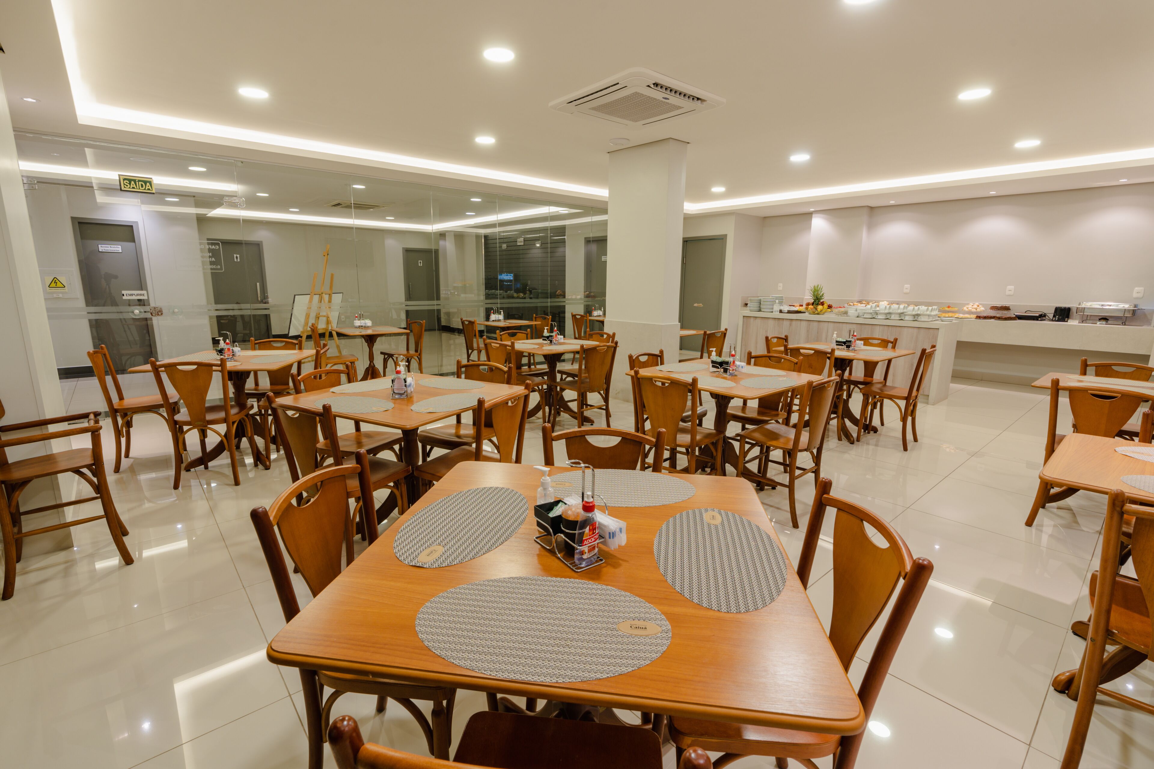 A spacious dining area with multiple tables and chairs, a buffet counter, and a clear exit sign.