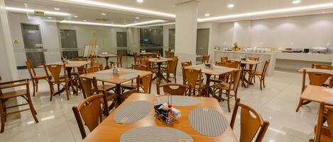 A spacious dining area with multiple tables and chairs, a buffet counter, and a clear exit sign.