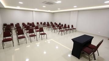 A conference room with rows of red chairs, a black table, and recessed ceiling lighting.