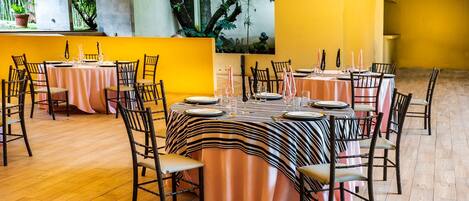 Un restaurante con varias mesas dispuestas para comer, con manteles a rayas y sillas de madera.